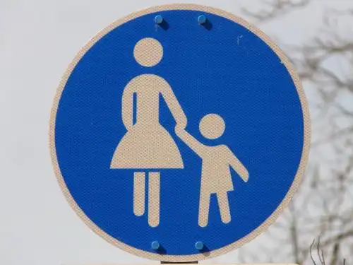 sidewalk,traffic sign,pedestrian,shield,woman,child