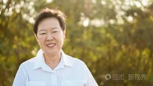快乐亚洲老年妇女微笑在早晨阳光与绿色自然背景