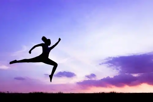 朝霞下跳跃的运动女生背影剪影