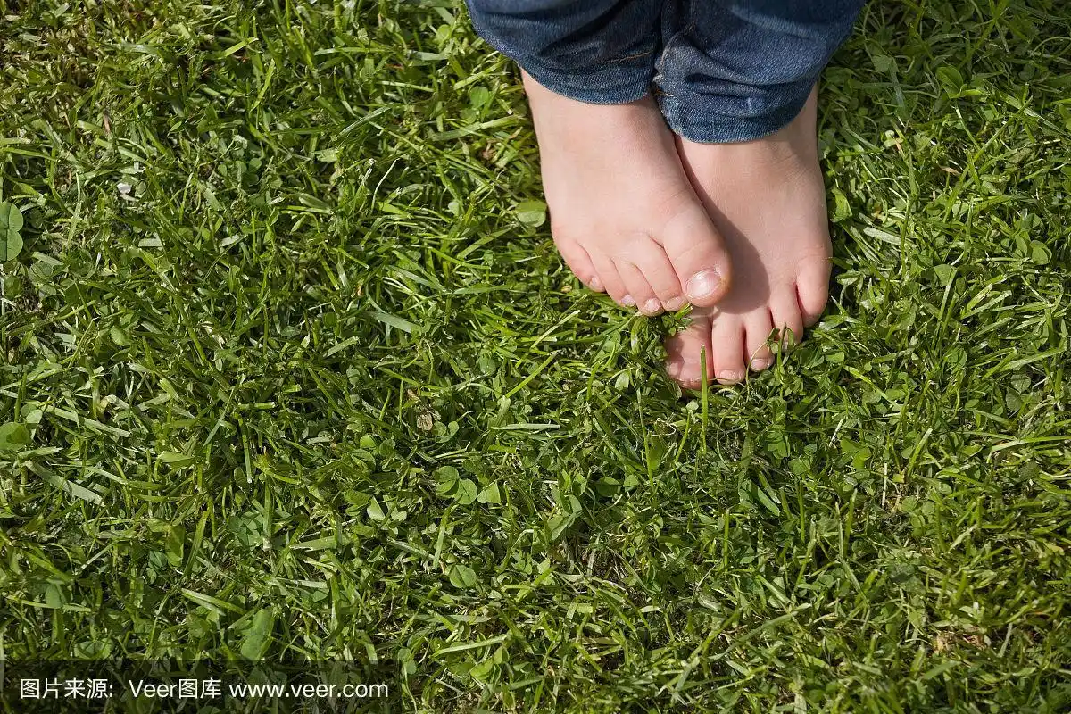 在一个阳光明媚的日子里,一个小男孩站在公园的草地上.孩子的光脚.