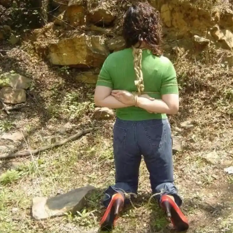 90年代被绑在绳子上的女犯人照片,镜头下的她头发泛黄,绿色紧身毛衣