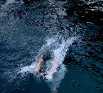 跳入水中当他跳入水中时,他把雌性溅到游泳池里女潜水员站在跳跃板上