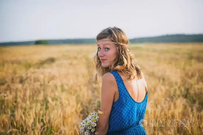 美丽的妇女与野花花束在手转过身来回头看大麦草甸