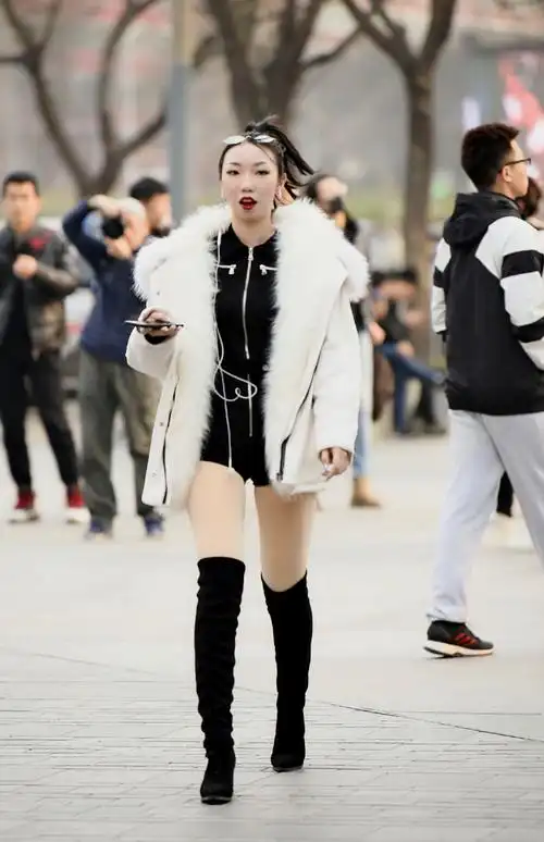这位女孩选择黑色过膝靴,搭配黑色百褶短裙 烟灰色休闲外衣,简约舒适