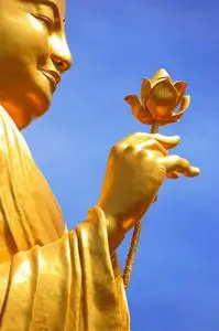 手捧莲花花金佛像,手捧花在蓝天上照片