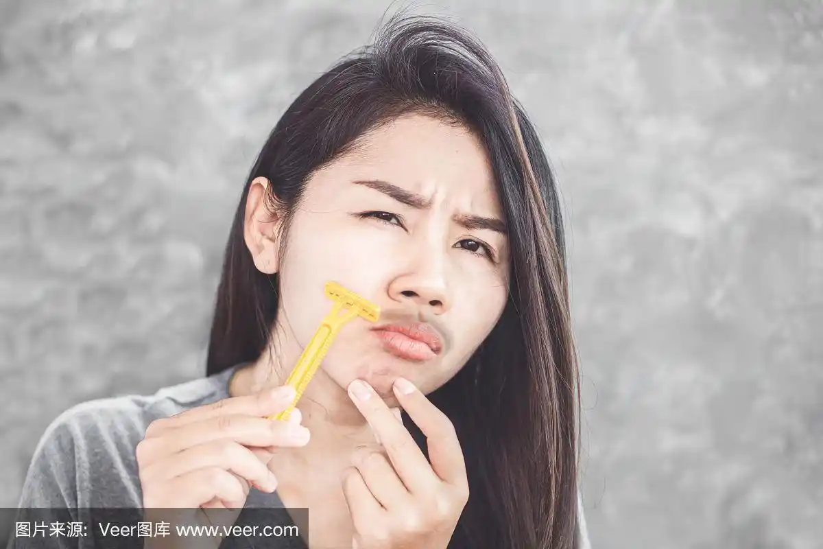 亚洲妇女用剃刀刮脸上的胡子