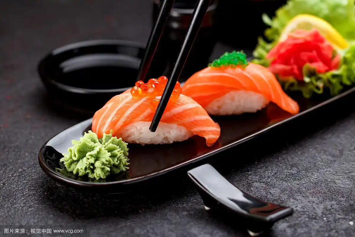 用筷子夹在黑色盘子里的三文鱼寿司手握寿司.