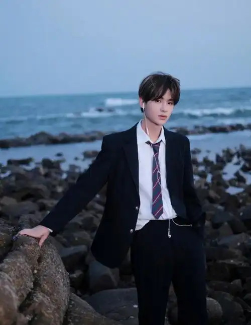 黄明昊海边氛围感写真,黑衣与礁石融为一体,帅气俊逸少年魅力