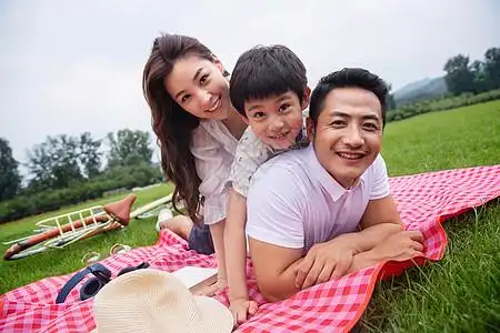水平构图男孩绿色幸福的一家三口趴在野餐垫上图片素材