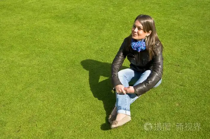 女孩坐在绿色的草坪上