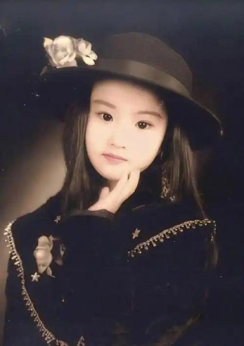 刘亦菲小时候的照片在镜头前很自然,托着下巴看着镜头,穿着当时流行的