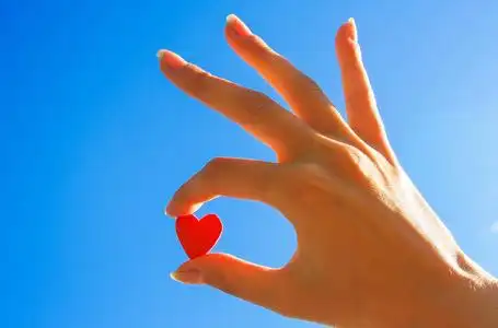 天空创造力在天空中的女人的手一颗红色的心照片