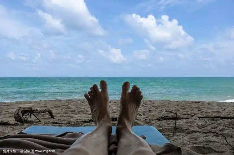 一个男人光着脚躺在阴凉的海滩上