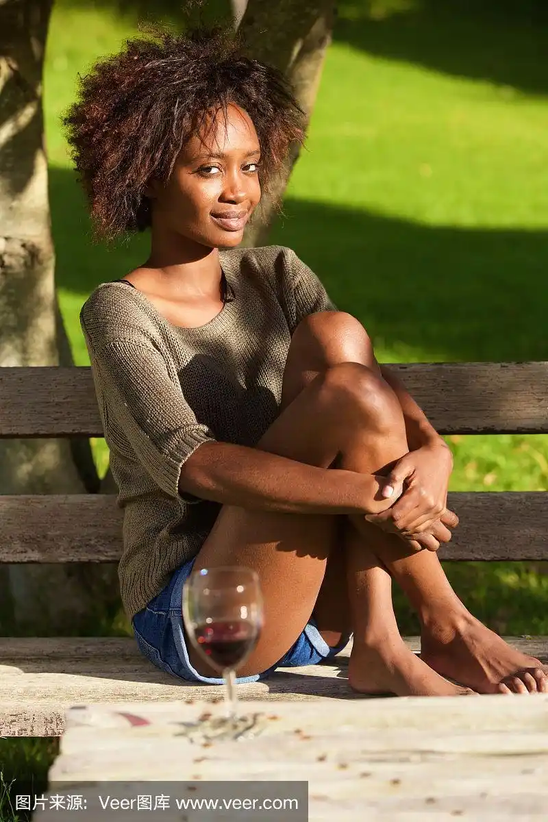 年轻的非洲裔美国女人赤脚坐在公园里