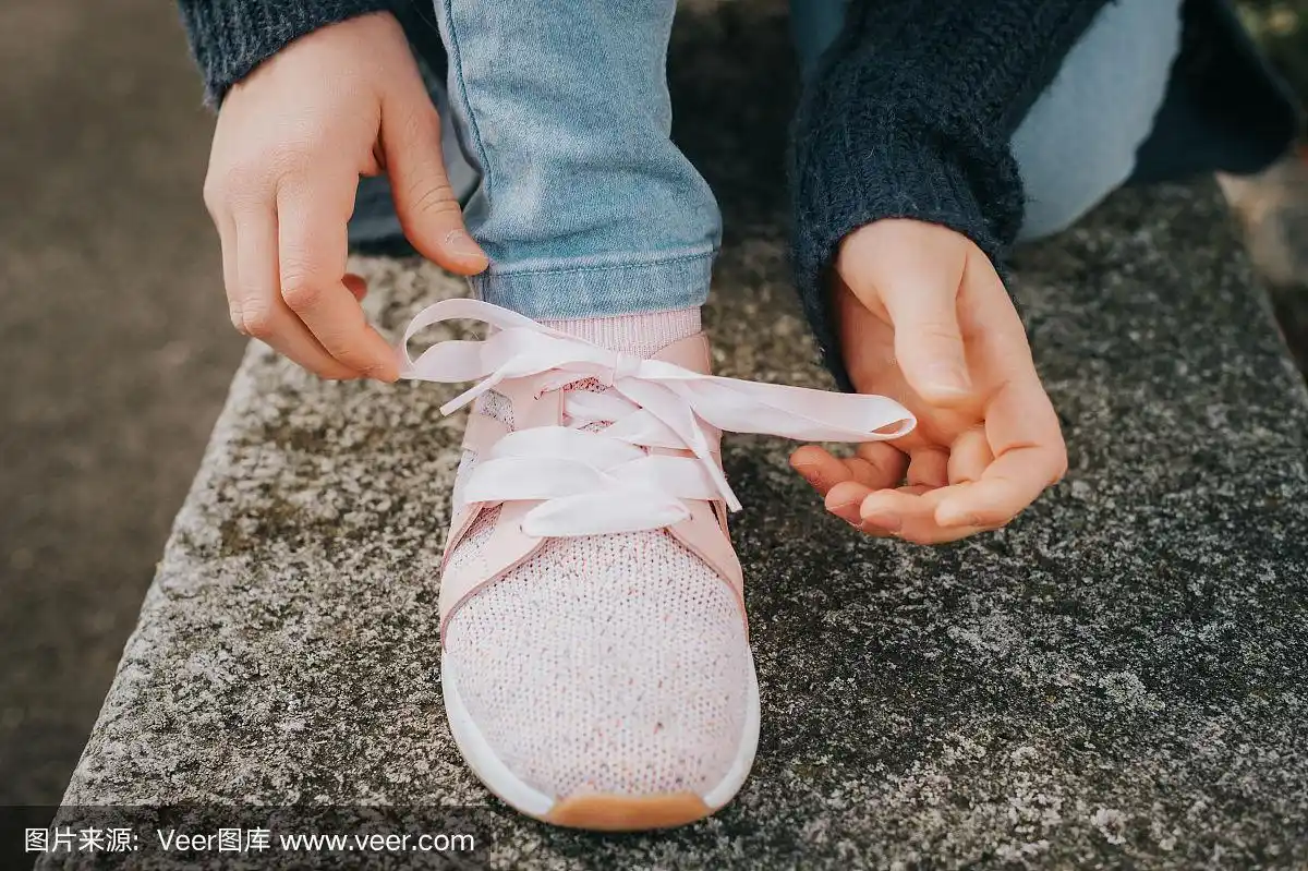 小女孩系着运动鞋,为幼小的孩子们穿鞋