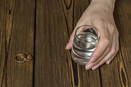 女性手拿一杯酒, 特写, 木质背景, 复印空间照片