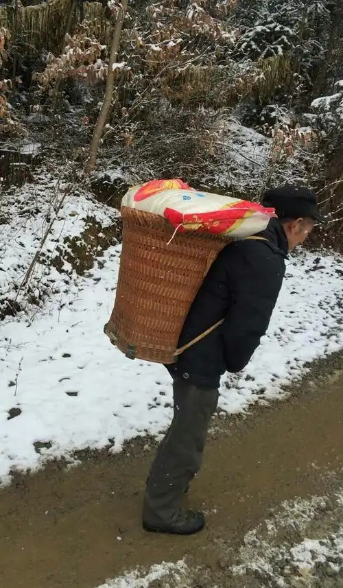 山路泥泞,车子通不过来,老人艰难的背着生活所需用品,又苦又累.