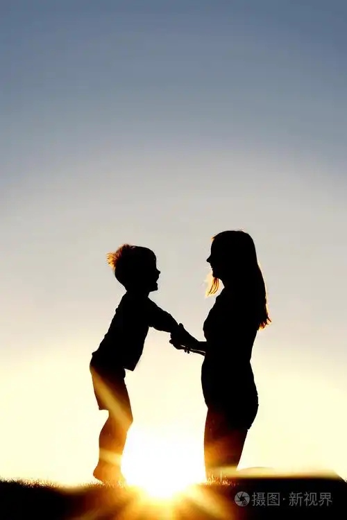 母亲和年幼的孩子手牵着手在日落时的剪影