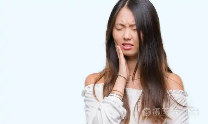 年轻的亚洲女人由于牙痛或牙齿上的牙齿疾病在孤立的