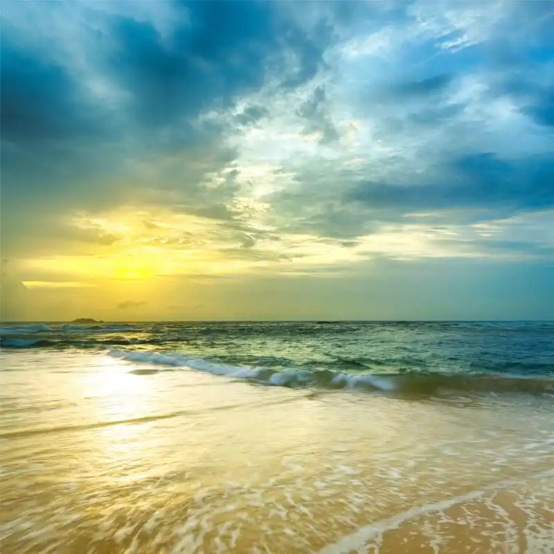 云朵在太阳的光照下,颜色呈现五彩缤纷,岸边还有很多白色的浪花.