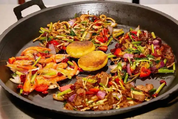 平锅烙锅使用的是铁锅,优点是受热均匀,传热快,食材入锅瞬间就能"滋滋