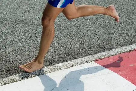 赛跑者的脚光脚跑步的特写运动青年男子在现代健身房特写的跑步机上