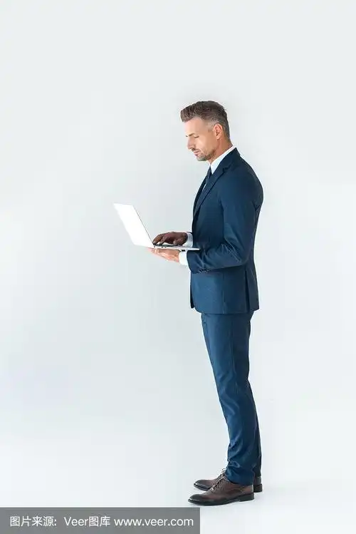 侧面的英俊的商人西装用笔记本电脑隔离在白色