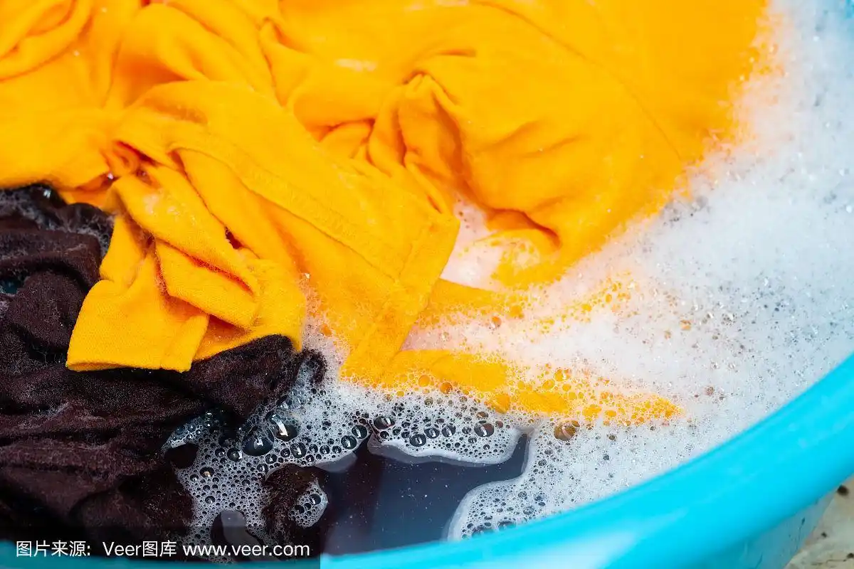 特写黄色和棕色的衣服洗在蓝色的盆.