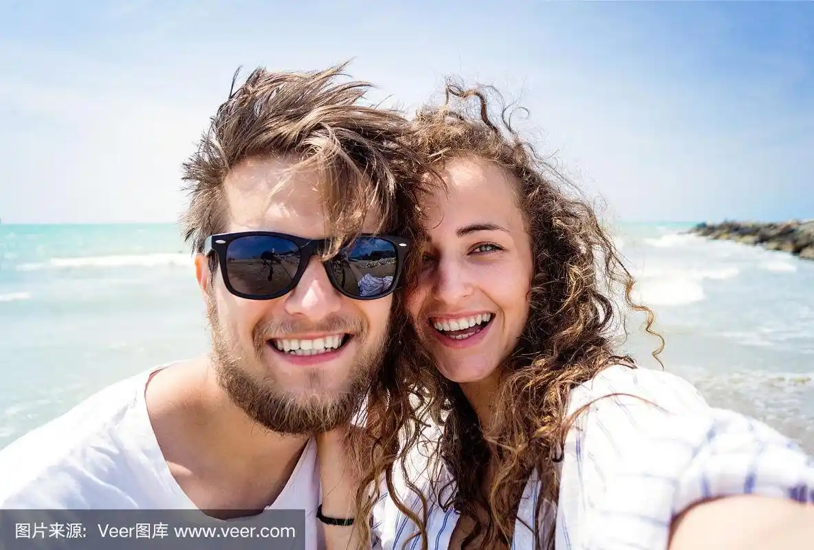 一对美丽的情侣在海滩上,大笑,自拍,微笑