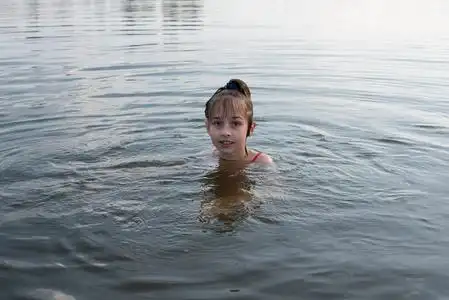 快乐美丽的小女孩在蓝色的水里游泳,露出水面微笑.