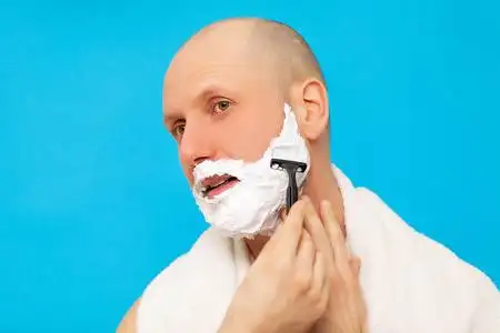 浴室里的男人用剃须刀刮胡子照片