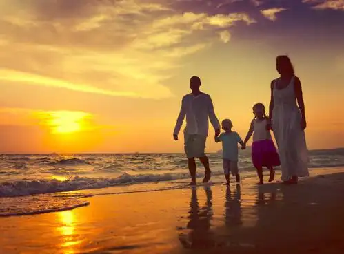 夕阳下海边快乐的一家四口