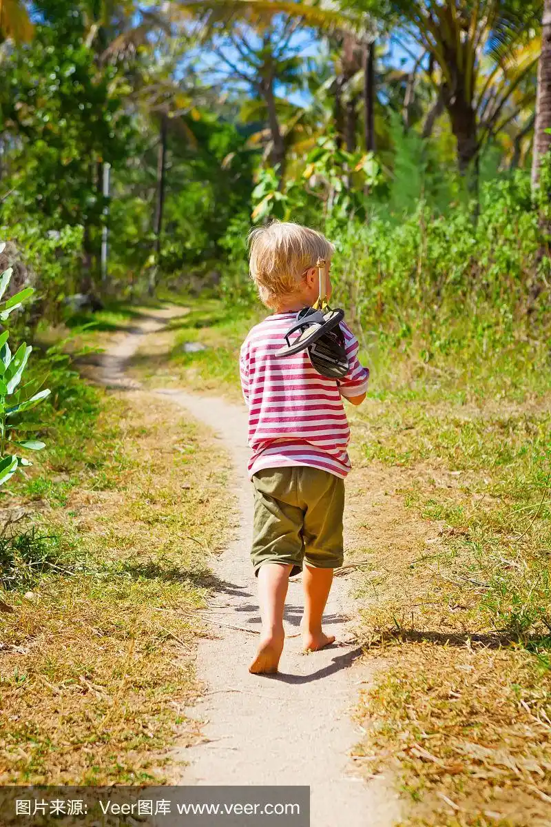 快乐的光着脚的孩子独自走在海滩上的丛林小路上