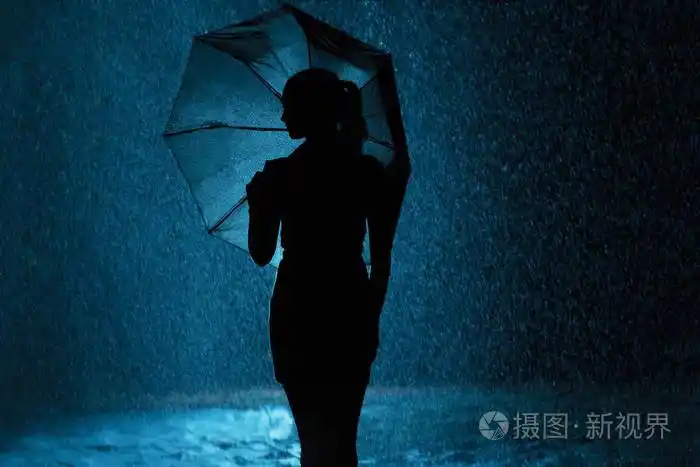 剪影少女的身影在雨中撑伞,一位年轻女子高兴地滴水,概念天气和心情照