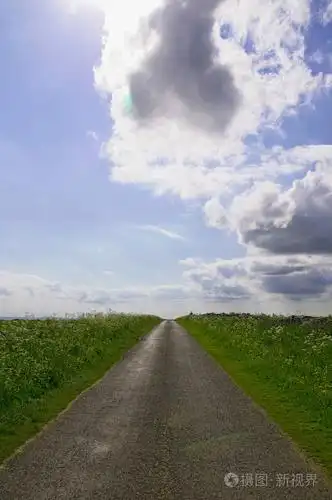 绿色田野之间的乡村景色,背景是天空中的云