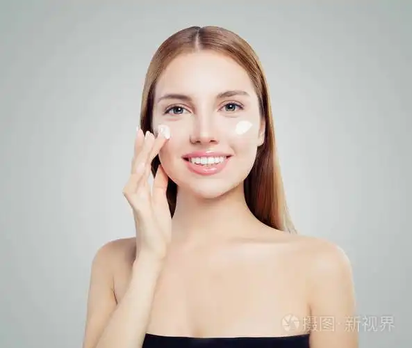 快乐美丽的女人在健康的皮肤上涂上奶油.