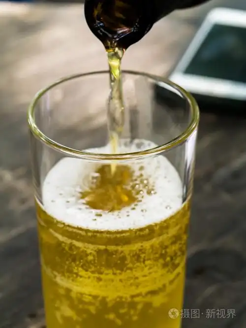 啤酒涌入木制的桌子上的玻璃照片-正版商用图片1nc028-摄图新视界