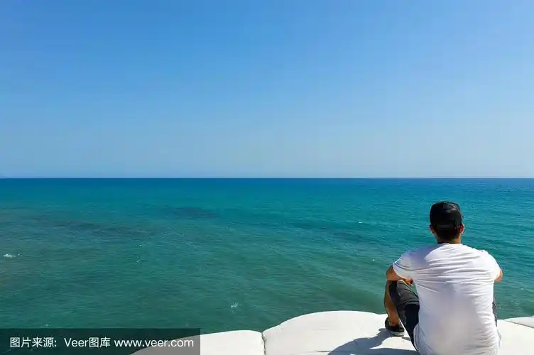 年轻人坐在悬崖上看热带海洋