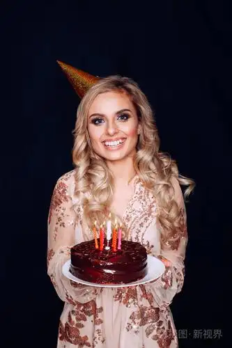 一个年轻漂亮的金发女孩拿着生日蛋糕和蜡烛的肖像照片-正版商用图片