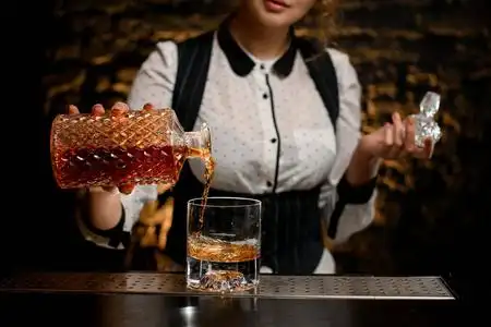 特写酒吧女招待小心地把酒瓶里的酒倒进玻璃杯里照片