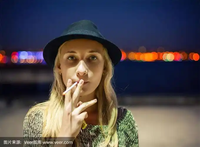 戴着帽子的年轻女孩在街上抽烟