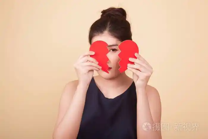 美丽的年轻亚洲女人在米色背景下心碎