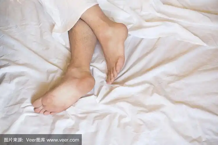 男光脚躺在床上的白色亚麻布上,选焦点