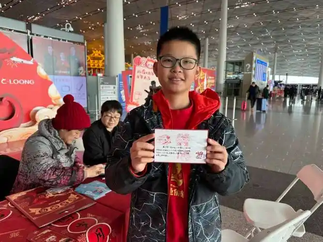 小旅客艾祺轩体验定制明信片活动/记者拍摄旅客郭郛老先生体验"写