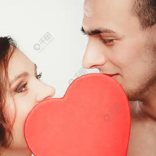 幸福恩爱的年轻夫妇在红色的心后面接吻裸体男人和女人与爱的象征符号