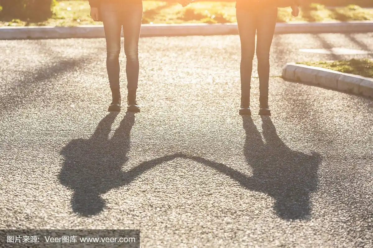 女双胞胎手牵手的影子在城市里.
