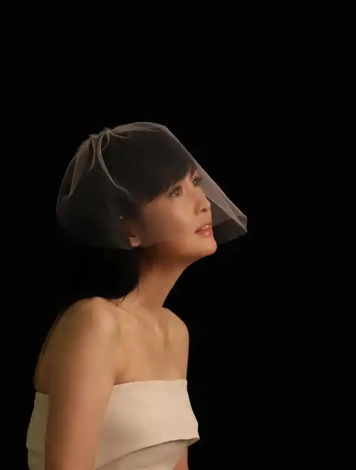 曝光的海报中周慧敏头披白纱,身穿露肩白色礼服,面露微笑,双手合十