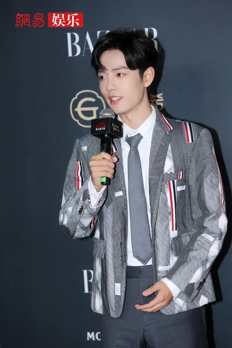 肖战身穿灰色拼接西装亮相,bazaar明星慈善夜,对镜头大方挥手微笑