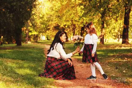 年轻的母亲和女儿在一个美丽的秋天一起在户外享受他们很高兴一个小