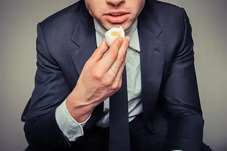 个坐办公椅上的商人正吃鸡蛋图片